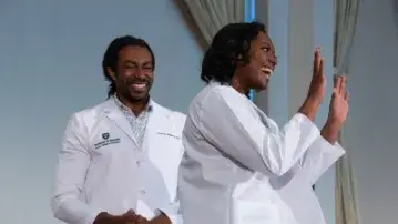 two people in white doctors coats on a stage