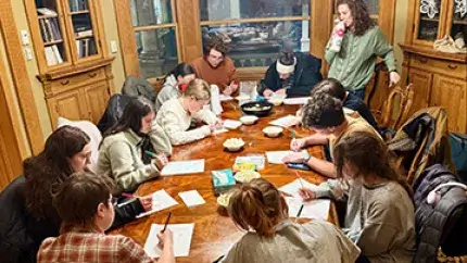 A group of students gather around a table.