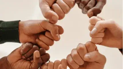 fists in a circle, photographed from below, a collective fist bump