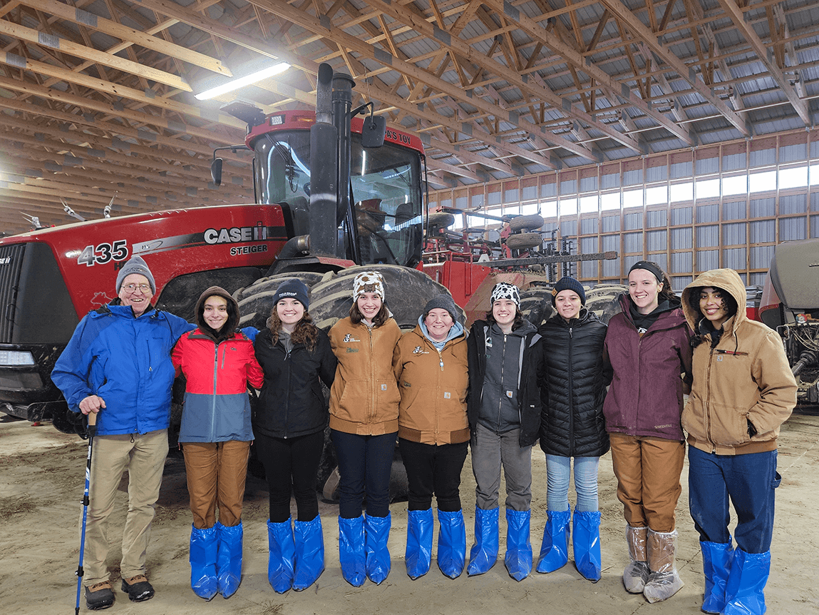 UVM students and faculty on the Winter Travel Dairy tour in a barn in Canada