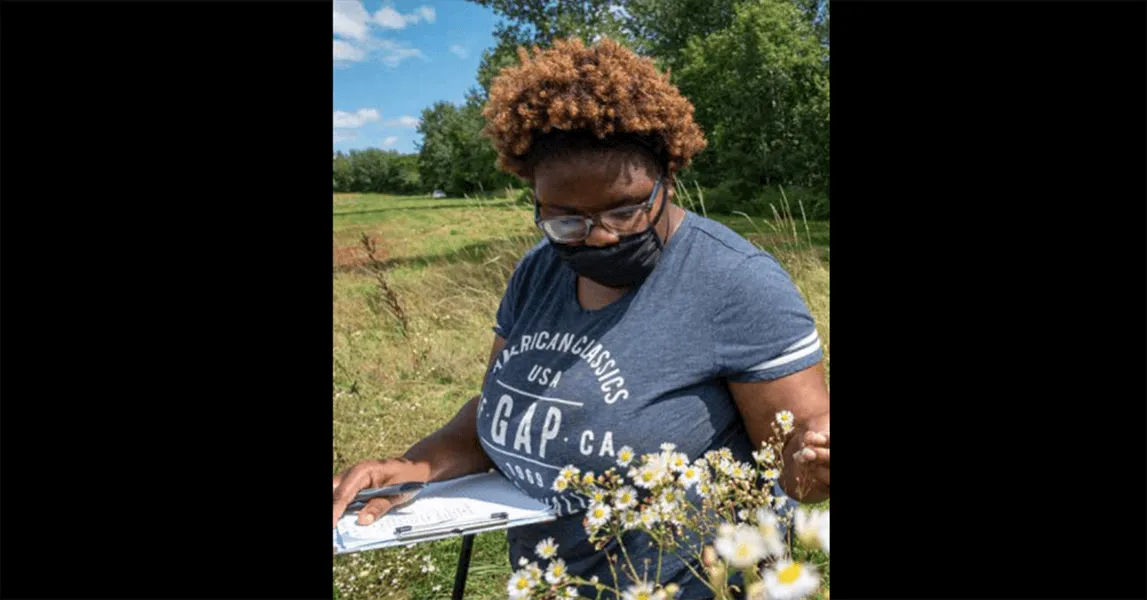 Jessica Cole out in a field, with flowers and a clipboard in hand