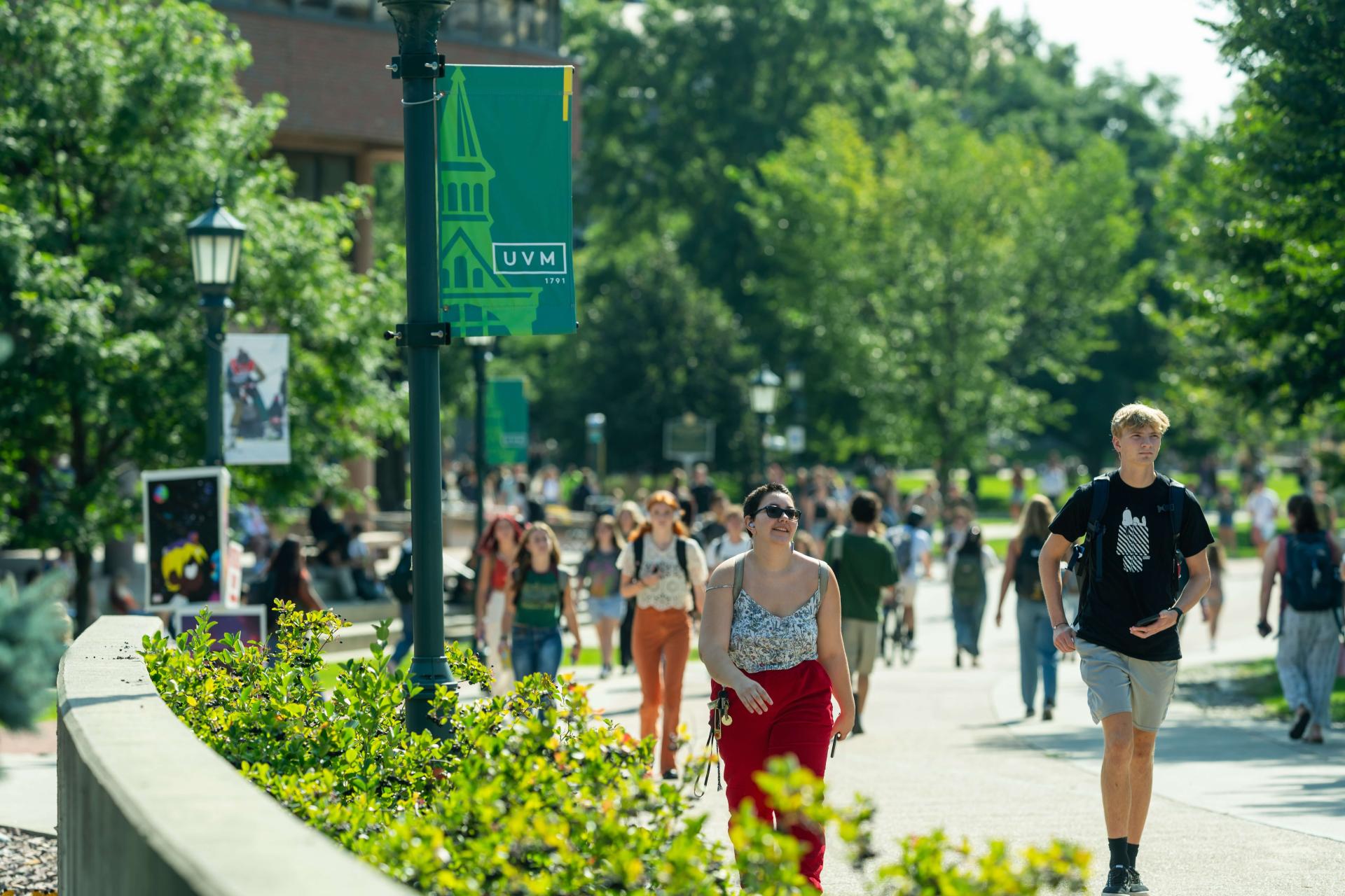 Students walk across campus on a sunny day.