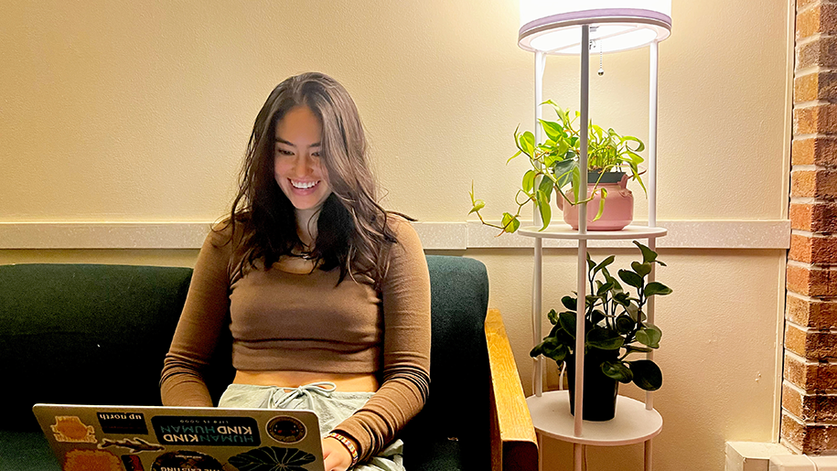 Julianna smiling while using a computer surrounded by houseplants
