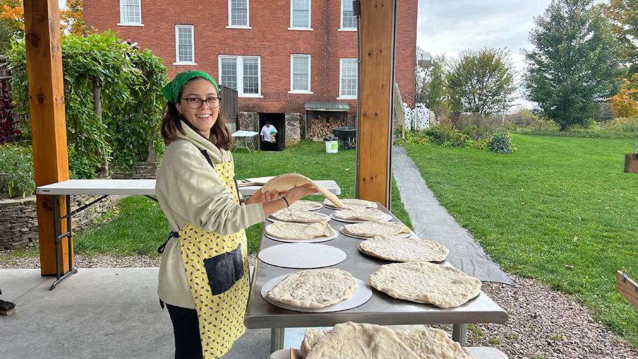 Lillian smiling while making flatbread in an outdoor setting