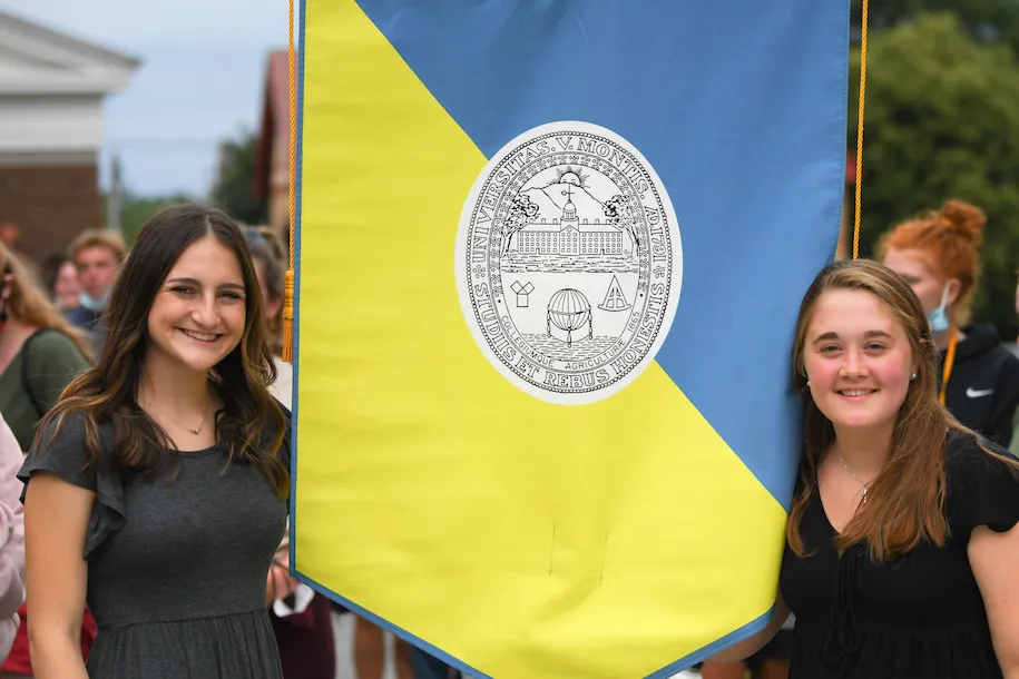 Maggie Sorrentino and Sarah Bassett hold the College Banner at CESS Orientation in 2021.