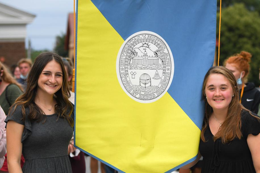 Maggie Sorrentino and Sarah Bassett hold the College Banner at CESS Orientation in 2021.