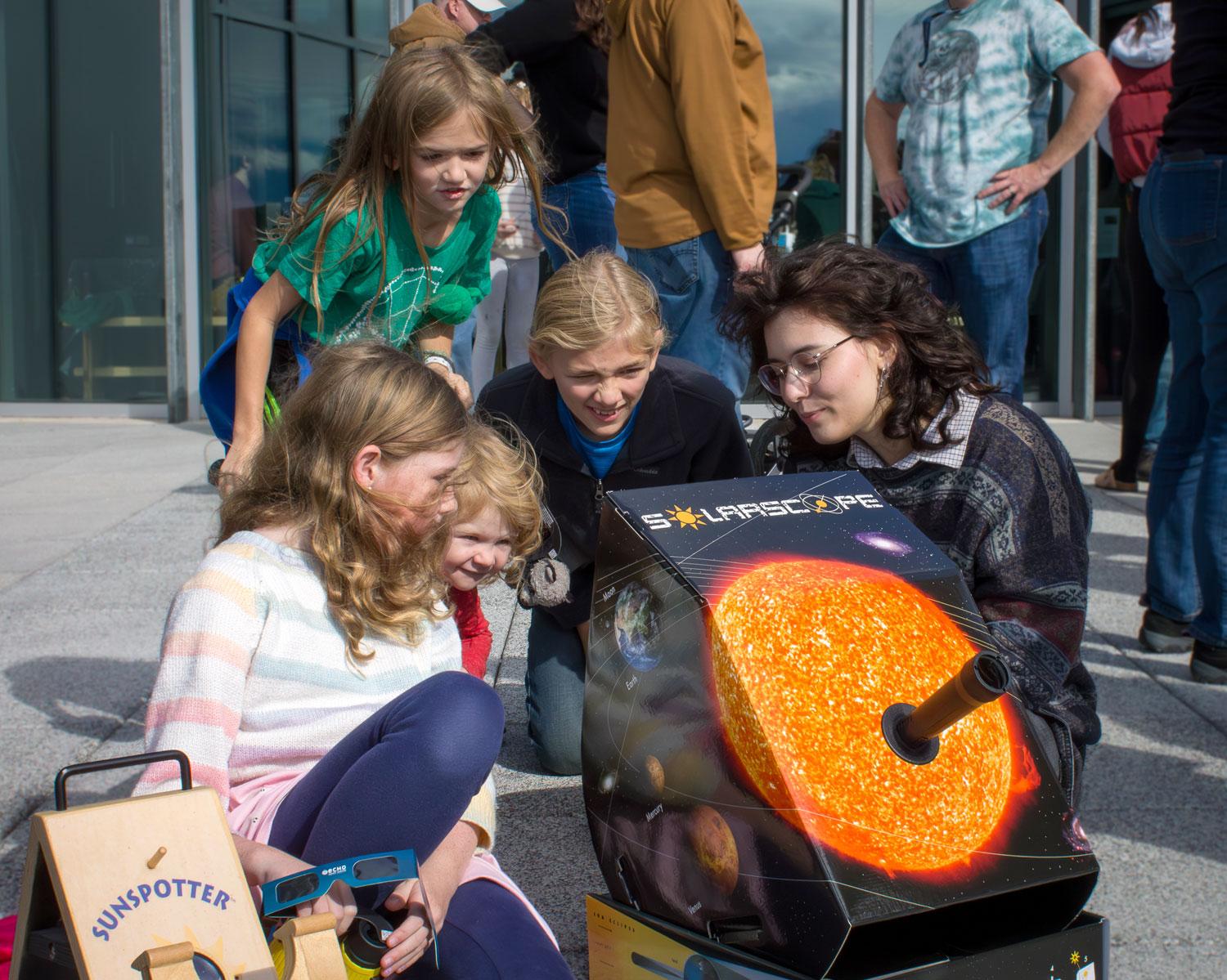 UVM SPS member Sarah Phillips helping visitors safely see a solar eclipse