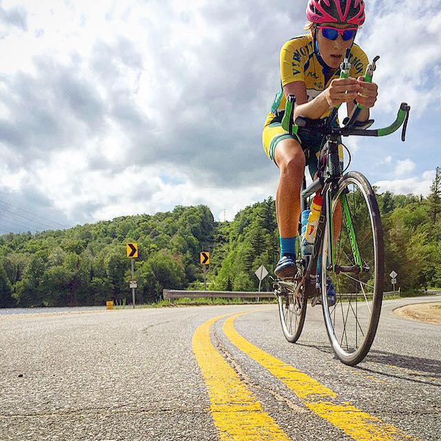 woman cycling on a road wearing a UVM triathlon race kit.