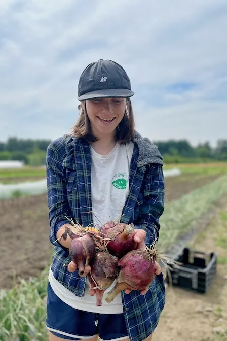 student holding onions in a field