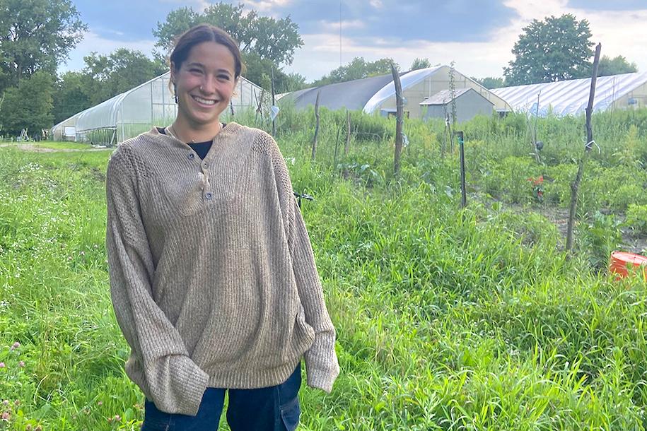 Abra Levin standing by greenhouses