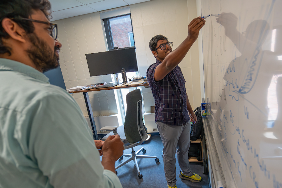 a student and professor working at a whiteboard
