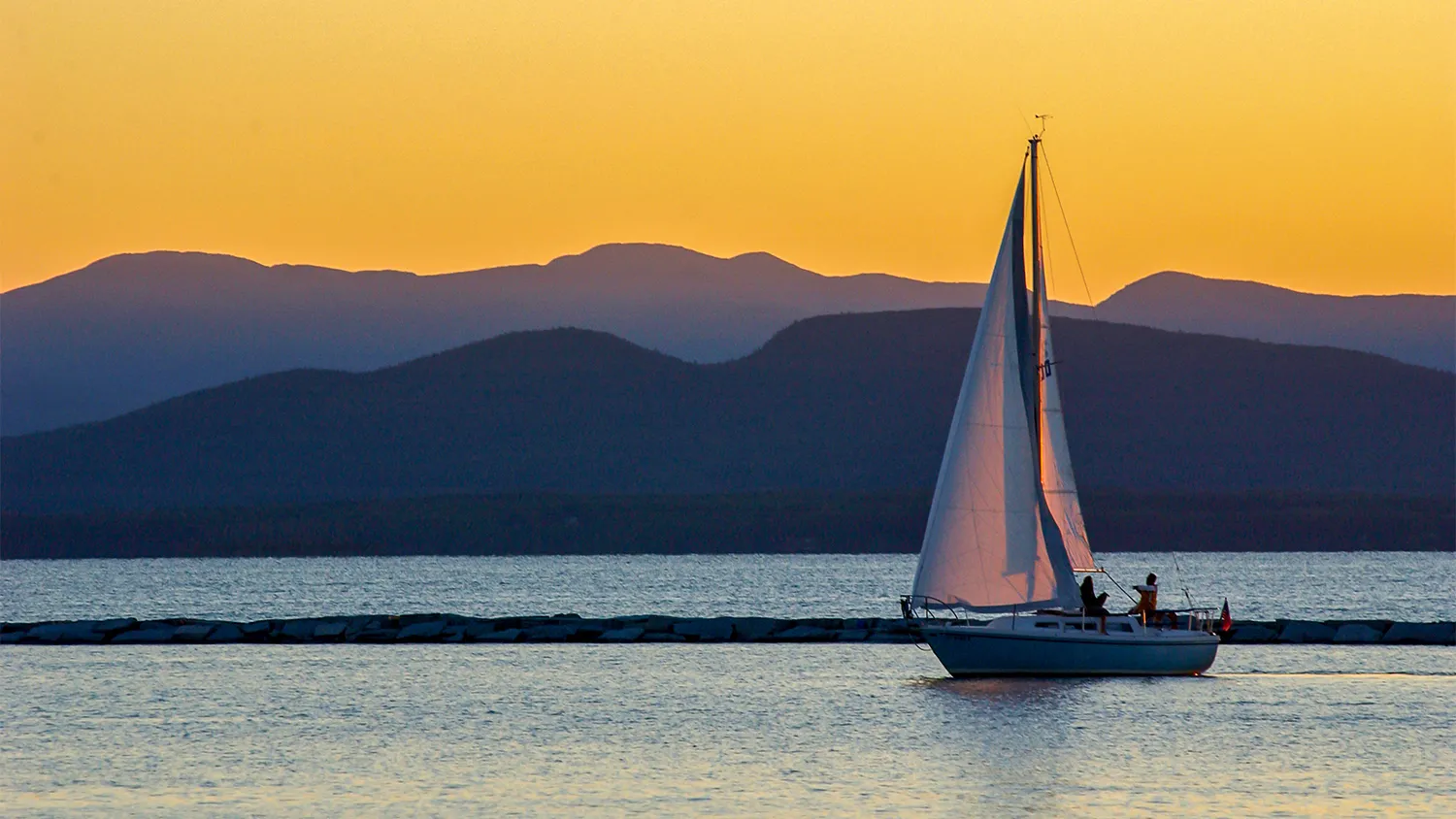 An image of a sailboat on Vermont's Lake Champlain at sunset. 