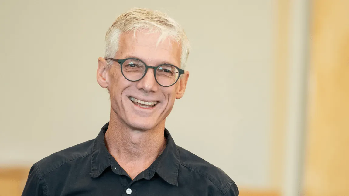Francis Churchill wearing a dark polo shirt and glasses