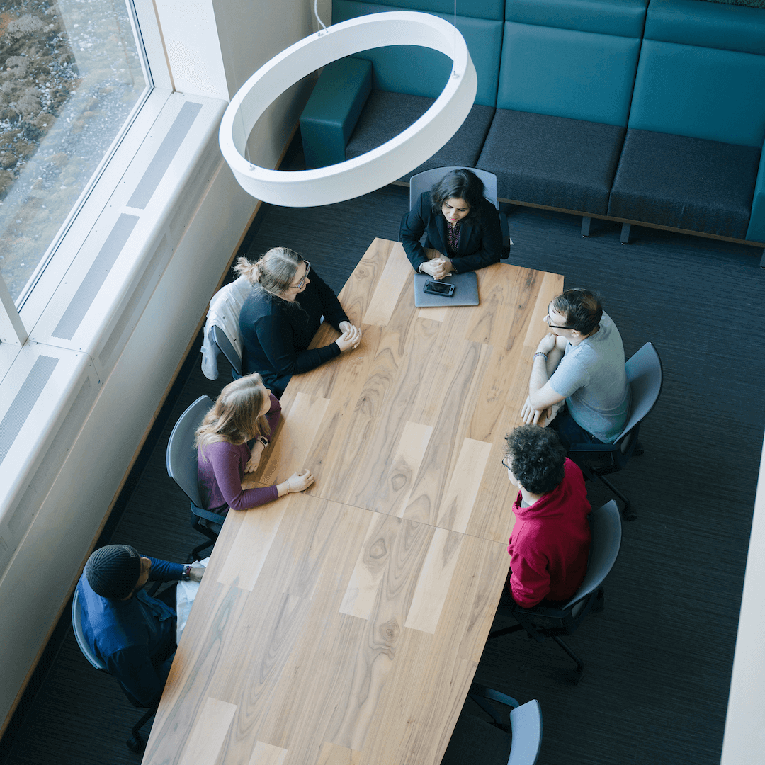 Bird's eye view of people sitting around a wooden conference room table