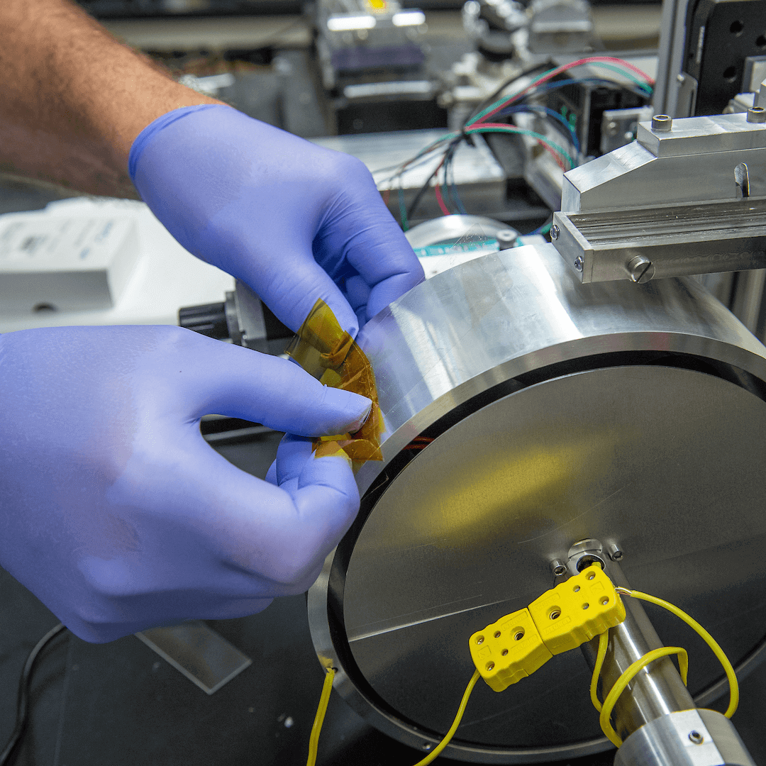 Hands placing a sticker on what looks like a metal wheel with wires attached