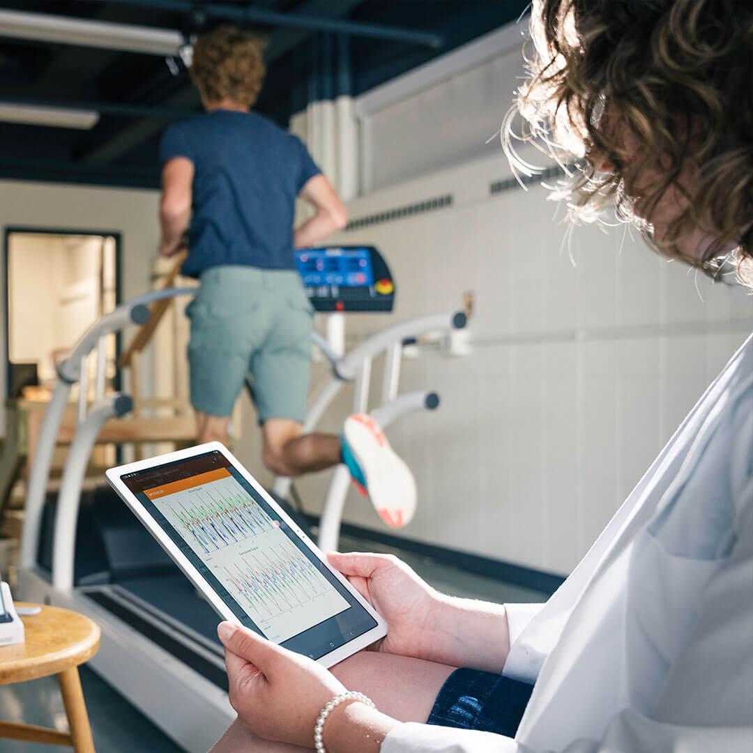 a person runs on a treadmill while another looks at bio data