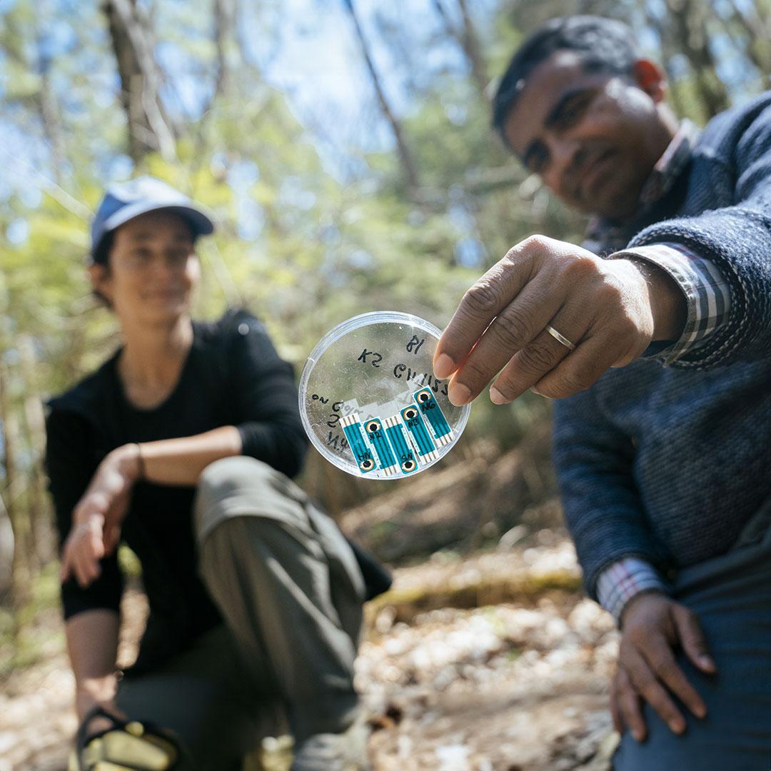 two people inspect a sensor removed from a river