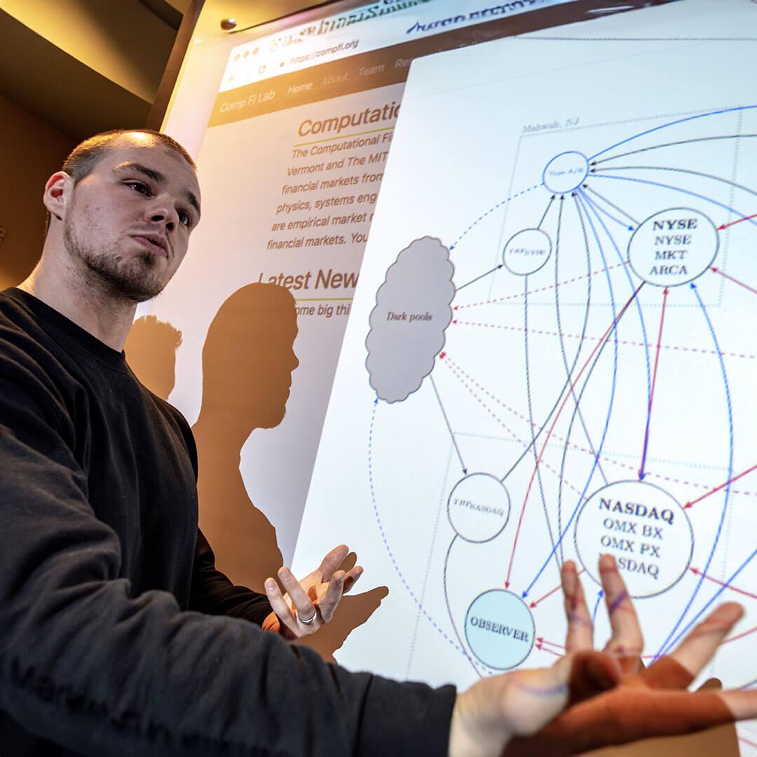 student presents in front of a projection of a graph