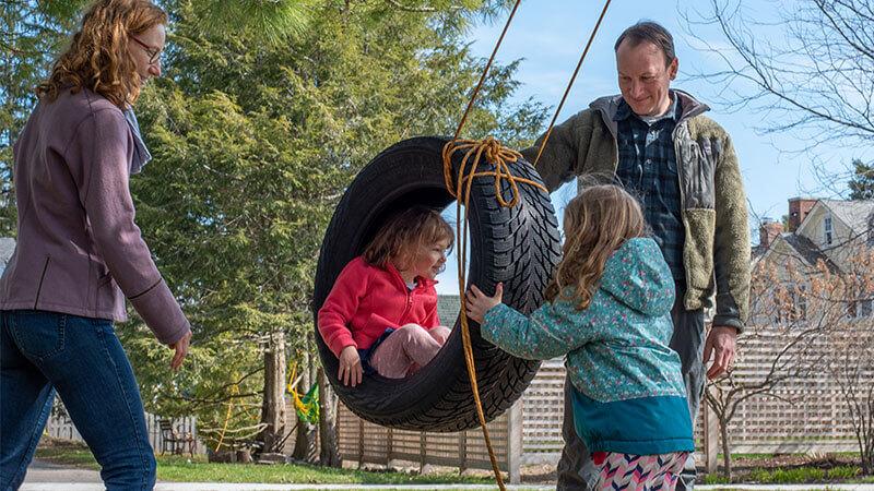 A family playing together with a tire swing