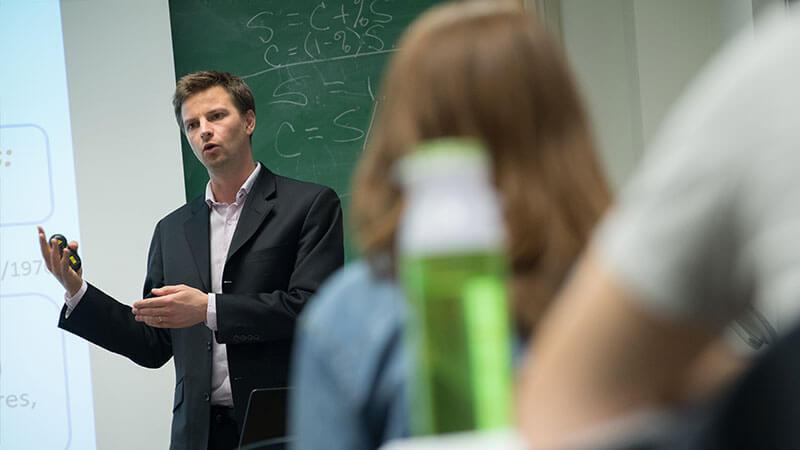 a professor talks at the front of a classroom