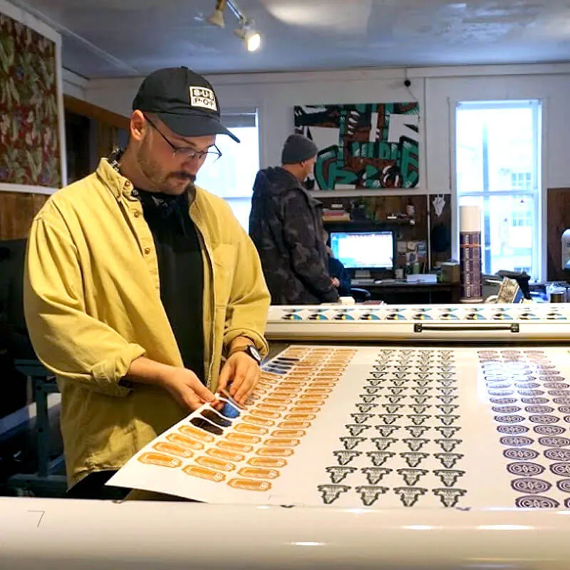 a student punches stickers out of a large sheet of paper