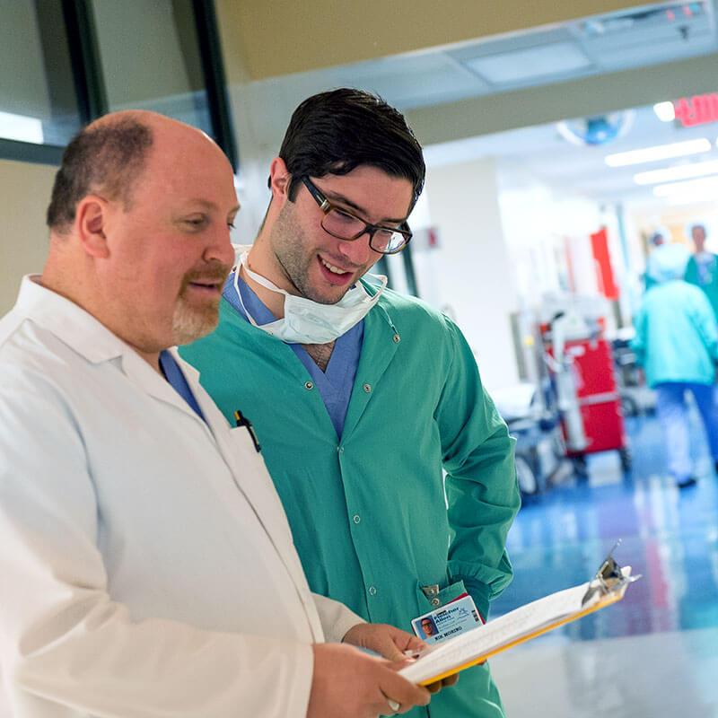 two people look at a clip board in a hospital hallway