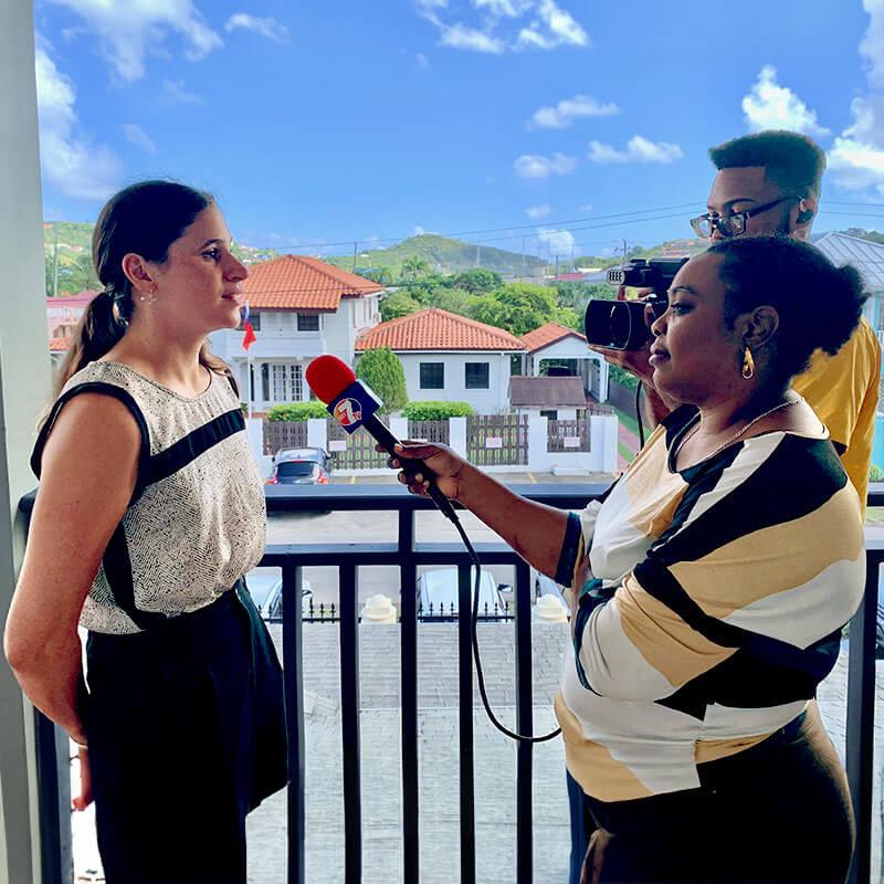 two people interview a third against the mountains of St Lucia