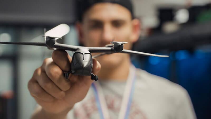 student holds a 3d printed airplane towards the camera