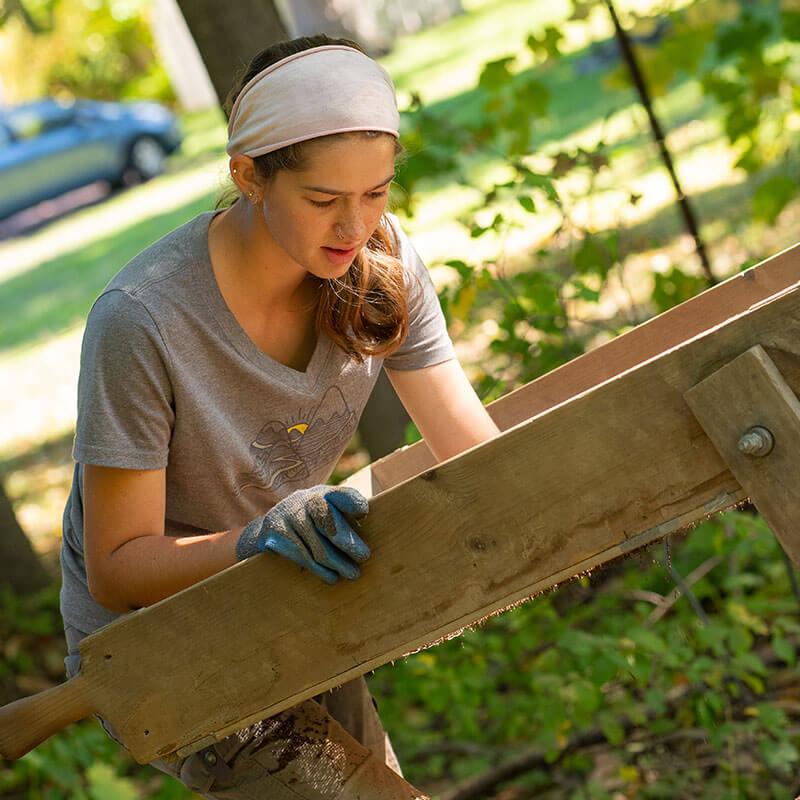 A person sifts through sand in a raised bed.