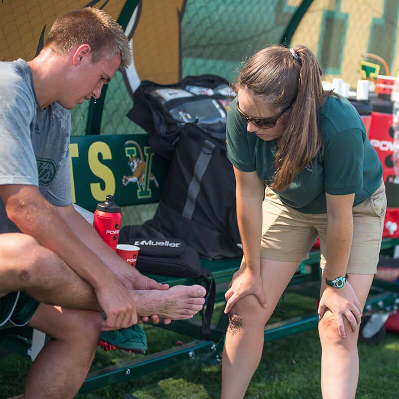 a student inspects the ankle of an athlete