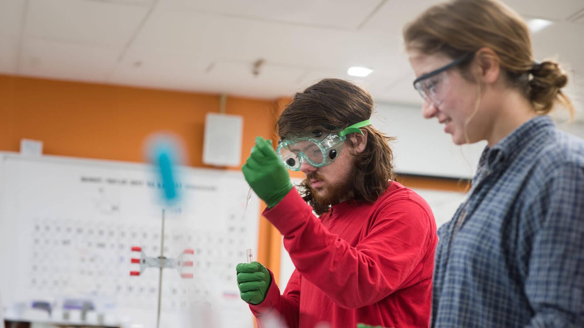 two students working with beakers in a lab