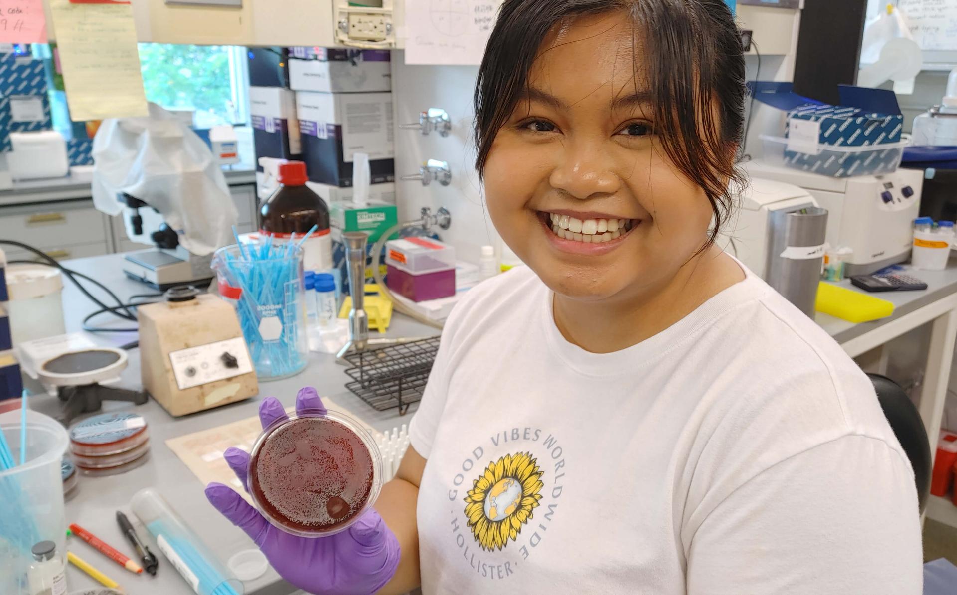 Graduate Student doing research in the lab shows her petrie dish