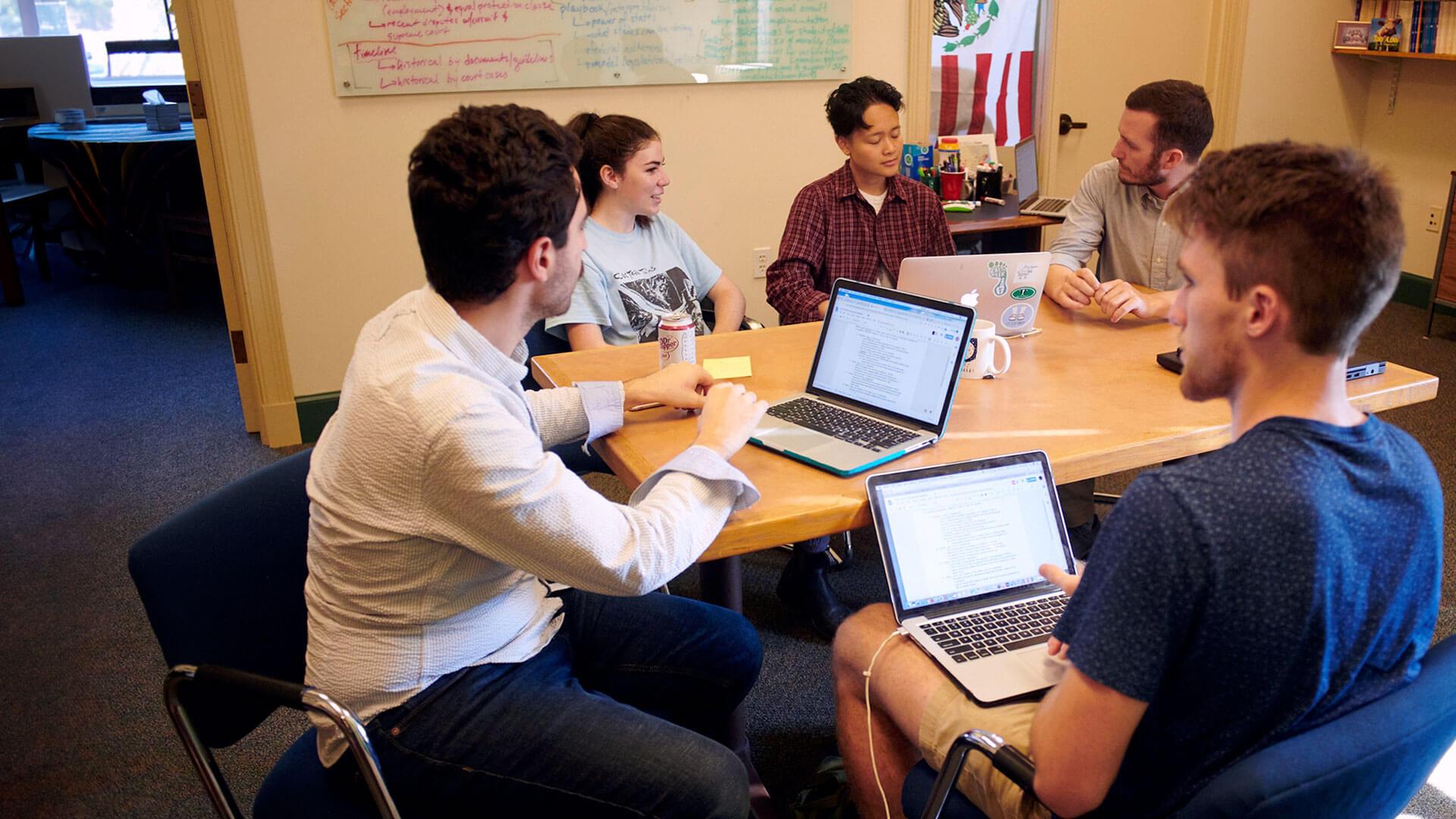 a group of people sitting around a desk talking