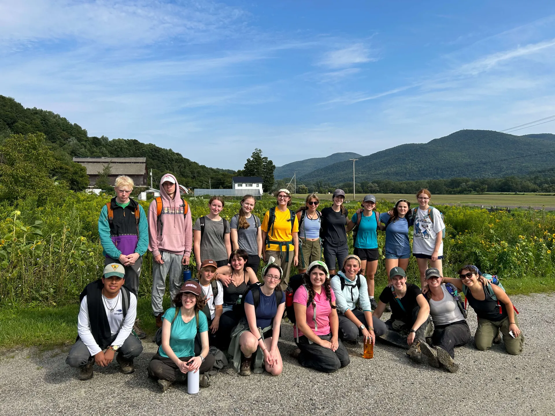 A group of SERVICE TREK students pose for a photo in a field during a beautiful sunny day 