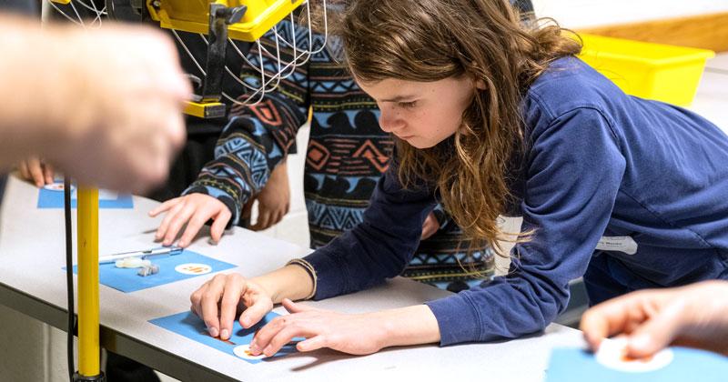 A young engineer learns about the process of using Photolithography to create art with representatives from GlobalFoundries