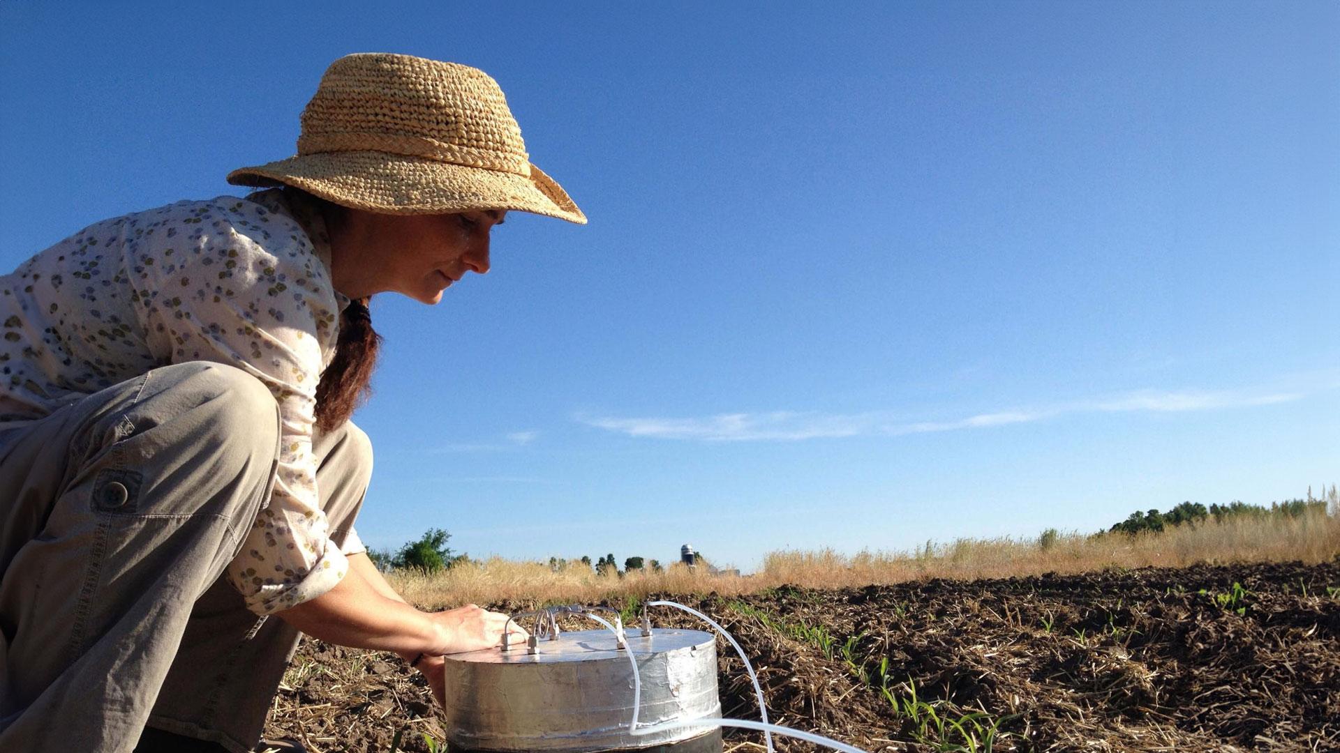 a person in a hat with buckets in a field