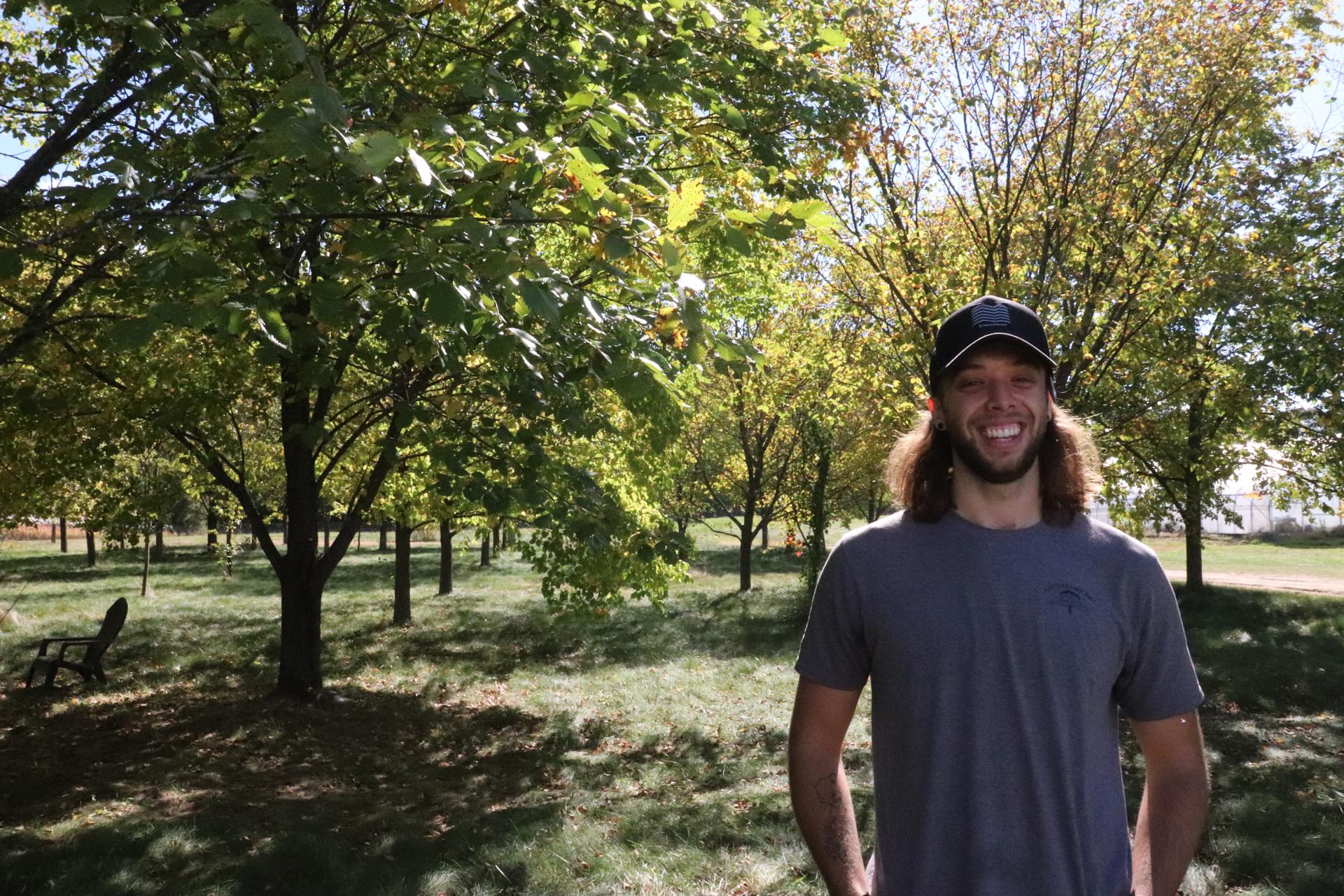 Student Ethan Pezzini stands in an apple orchard at the Horticulture Research and Education Center