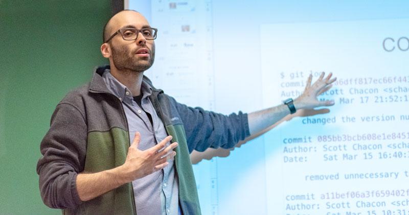 Professor providing a lecture with screen behind