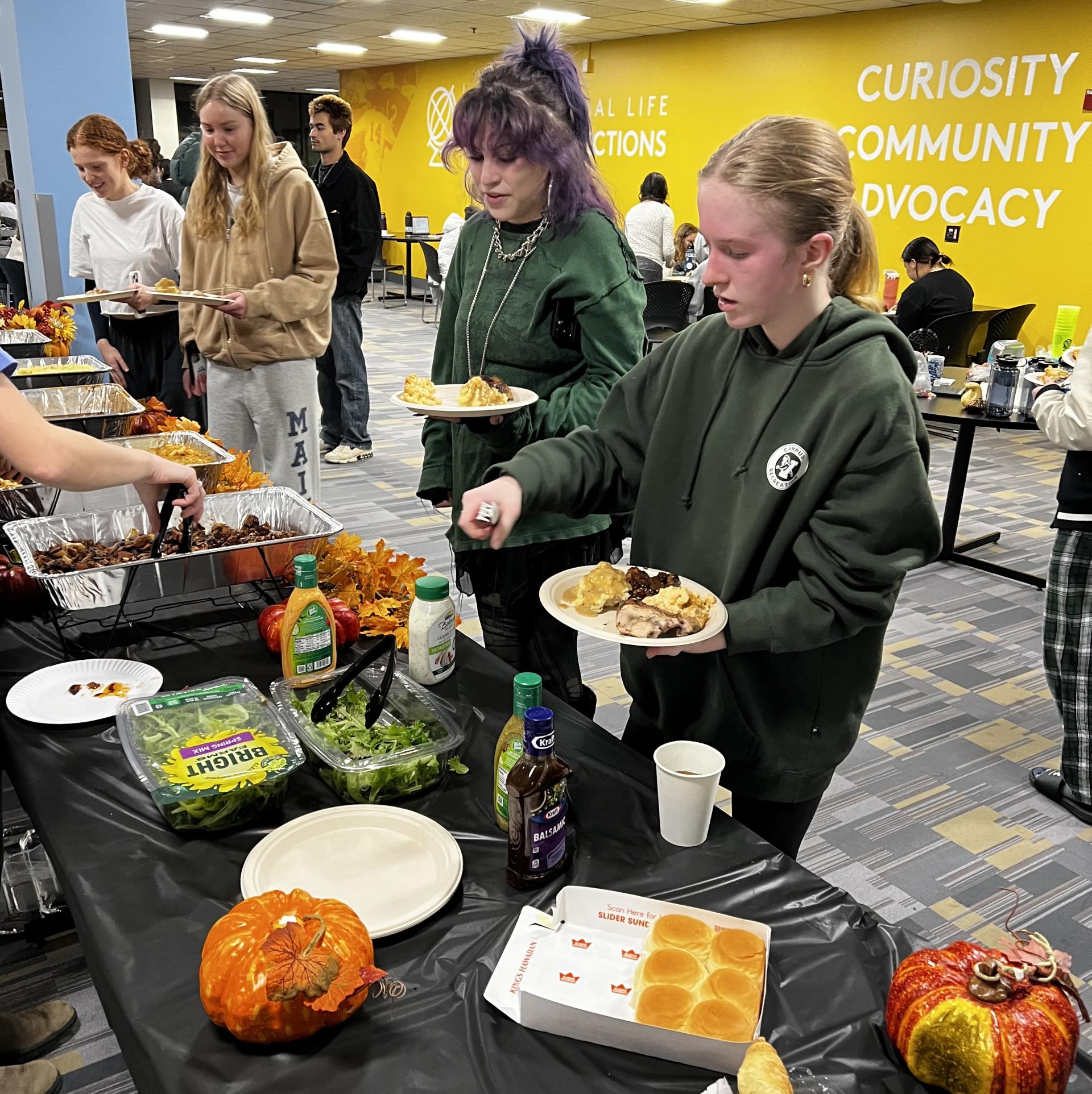 students getting food at a friendsgiving