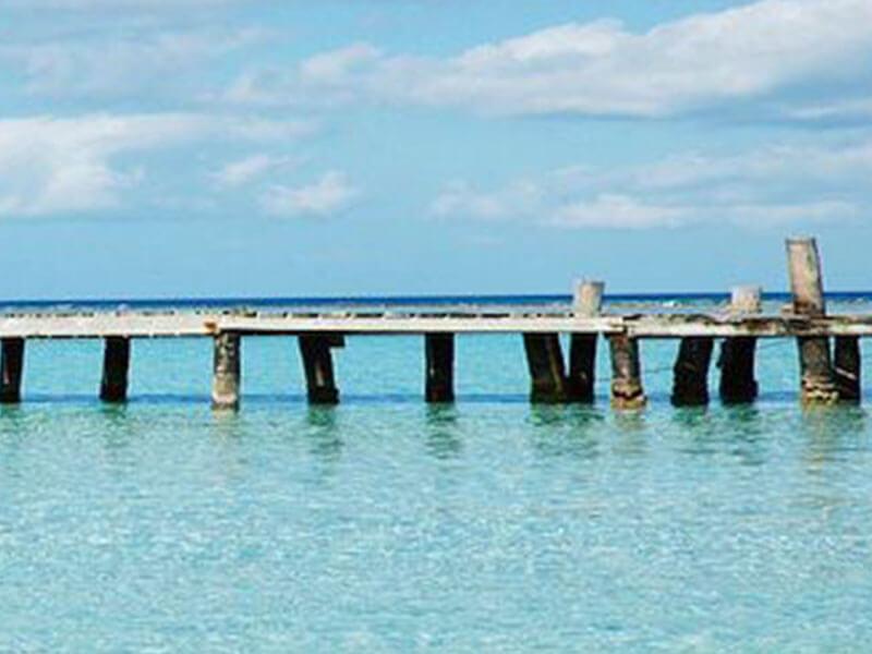 a long wooden bridge against a crystal blue water