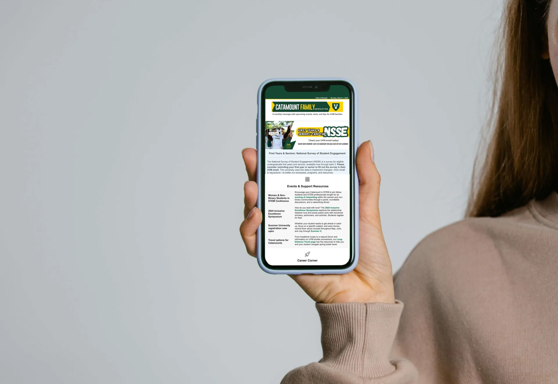 A hand holding an iPhone, it's screen displaying an issue of the Catamount Family Newsletter