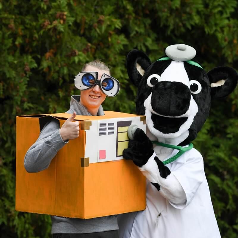 Student in googly eyes posing with Person in cow doctor costume