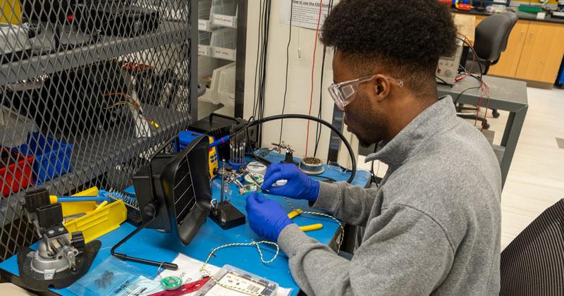 A student working at the soldering station in the SEED lab