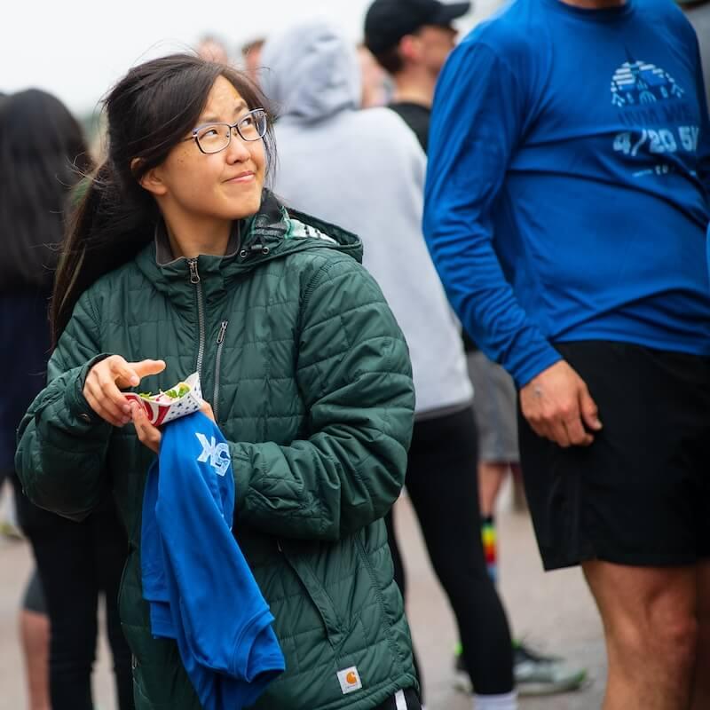 Student holding food and a running shirt at a 5k running event.