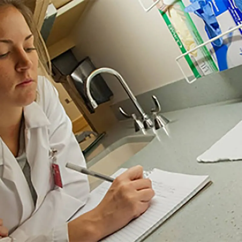 Person writing on a notebook in a research lab