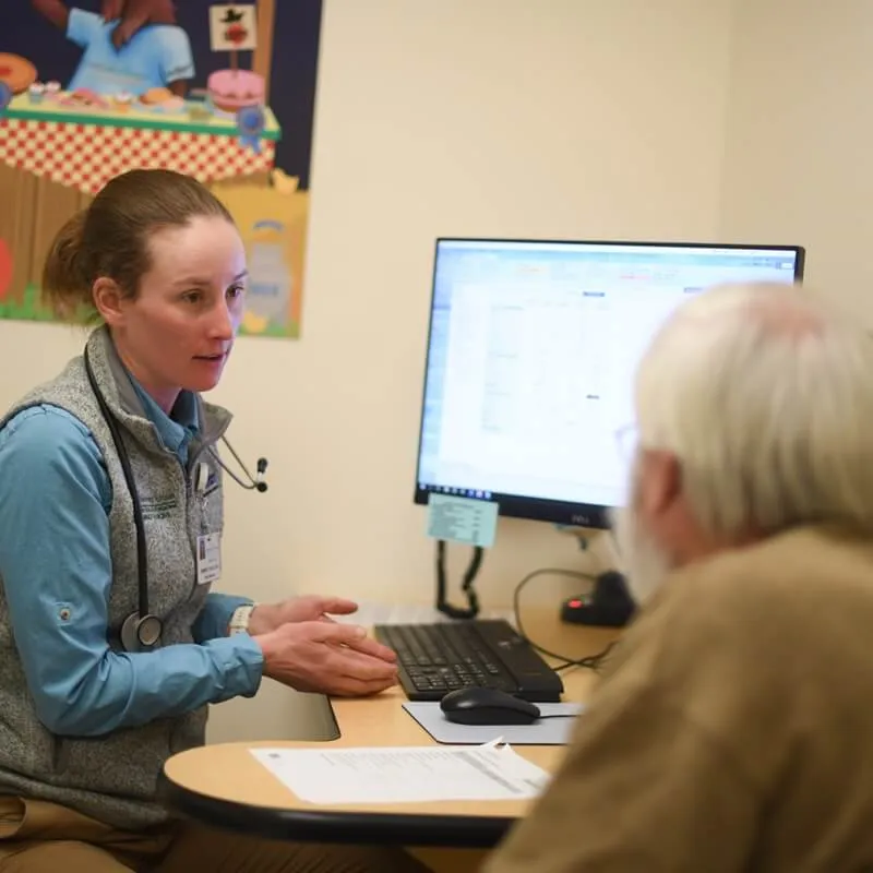 clinician talks with patient at desk