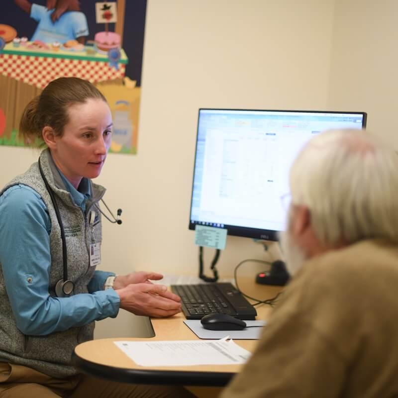 clinician talks with patient at desk