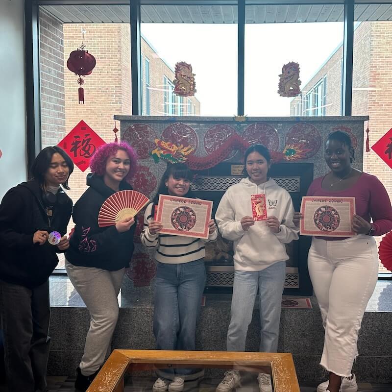 Students holding traditional fans and decorations associated with Lunar New Year.