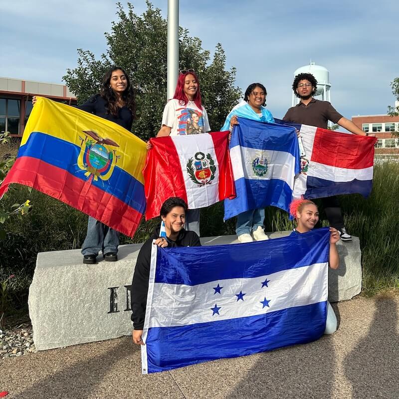 Students holding a variety of flags representing Hispanic countries. 