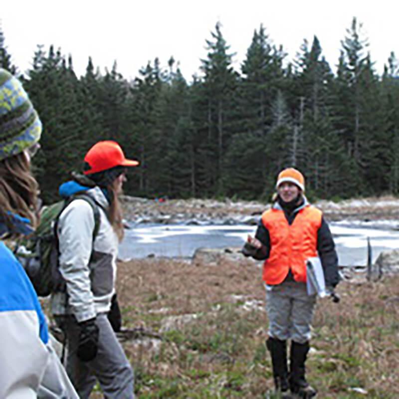A group of people standing in a field with a lake in the background